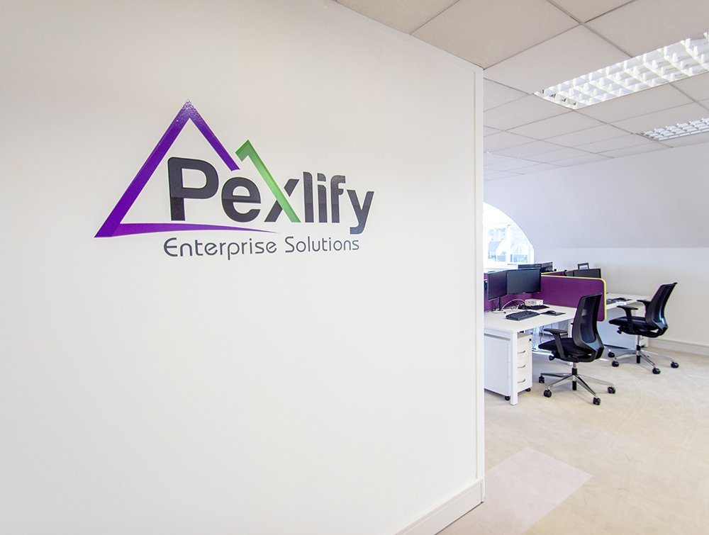 Pexlify Logo On White Wall With Desks In Background