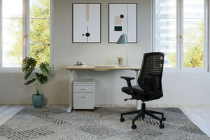 RoundE Bamboo Sit Stand Desk with White Pedestal and Black Armchair in Home Office Setting