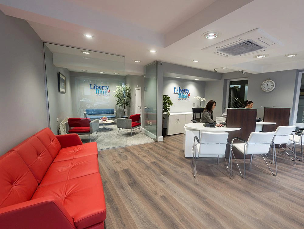 Several White Chairs Around Desks With Red Couch In Foreground