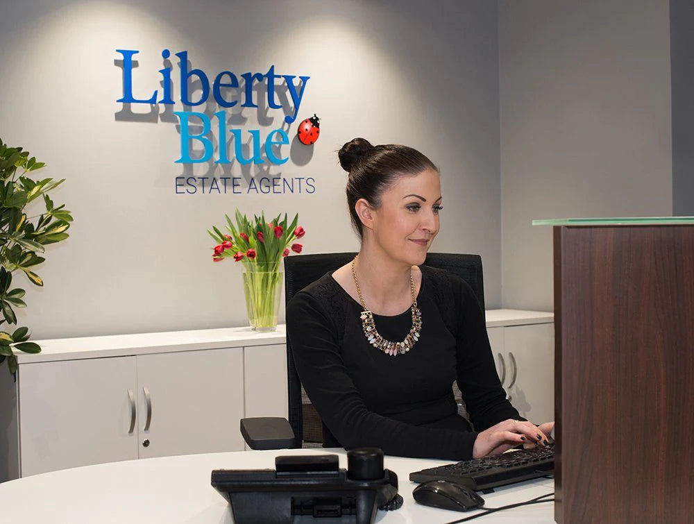 Woman In Black Typing On Keyboard In Front Of Liberty Blue Logo_B7B187B0 34Ff 4447 8Ed7 0174083A8Ac6