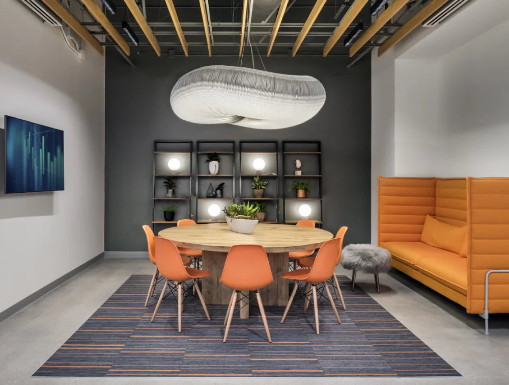 Wooden Round Table Office Furniture With Upholstered High Back Sofa And Bookshelves In Breakout Setting